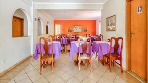 A dining area with tables set for guests, featuring purple tablecloths and wooden chairs. - Agrishow 2026 - Quarto Single e Duplo  (Ribeirão Preto)