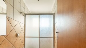 A bathroom with a toilet, sink, and frosted glass shower door. - Agrishow 2026 - Quarto Single e Duplo  (Ribeirão Preto)