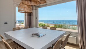 Un comedor con una mesa blanca, sillas de mimbre y vistas al mar.
