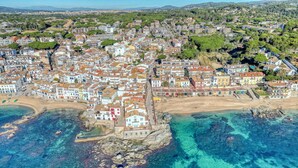 Vista aérea de un pueblo costero con edificios, una playa y aguas azul turquesa.
