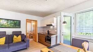 A modern kitchen with wooden cabinets, a built-in oven, and a dining area with a table and chairs. - Apartment 'Rose' with Private Terrace, Shared Garden and Wi-Fi (Bad Peterstal-Griesbach)