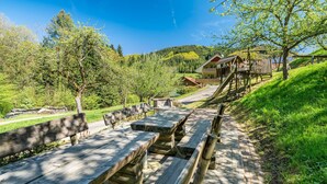 A wooden deck with benches, a wooden staircase, and a building with a balcony in a green, hilly area. - Apartment 'Rose' with Private Terrace, Shared Garden and Wi-Fi (Bad Peterstal-Griesbach)