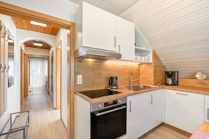 Eine moderne Küche mit weißen Schränken, einem schwarzen Backofen, einer Edelstahl-Dunstabzugshaube und einer Holz Arbeitsplatte.