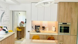 Eine moderne Küche mit Holzschränken, einer Marmorarbeitsplatte, einem Einbauofen und einer Pendelleuchte.