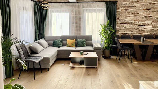 Ein modernes Wohnzimmer mit einer Eckcouch, einem Couchtisch und einem Essbereich mit Stühlen.