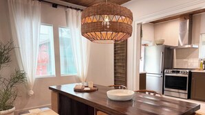 A modern kitchen with a wooden dining table, a large woven pendant light, and a built-in oven. - poolside getaway w/hot tub & relaxing courtyard (Houston)