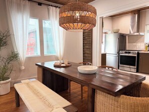 Eine moderne Küche mit einem Holzesstisch, einer großen gewebten Pendelleuchte und einem eingebauten Backofen.