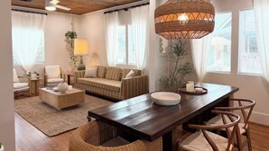 A cozy living room with a wooden ceiling, a dining table with chairs, a sofa, a lamp, and a large wicker pendant light. - poolside getaway w/hot tub & relaxing courtyard (Houston)
