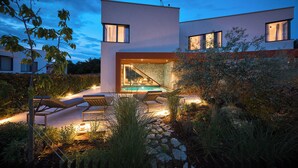 Uma casa moderna com piscina, área de estar externa e um muro de pedra.