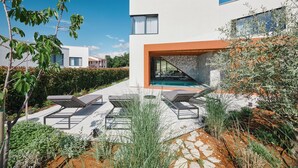 Uma casa moderna com piscina, área de estar externa e um caminho de pedra.