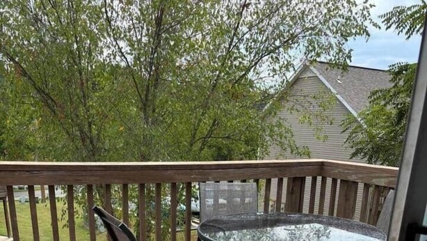 Une terrasse en bois avec une table en verre et quatre chaises.