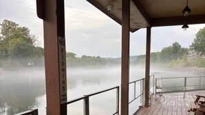 Une terrasse en bois avec une balustrade donnant sur un lac brumeux.