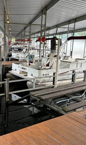 Un muelle cubierto con varias embarcaciones amarradas, una cubierta de madera y una barandilla de metal.