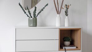 Un mueble blanco con tres jarrones que contienen plantas.