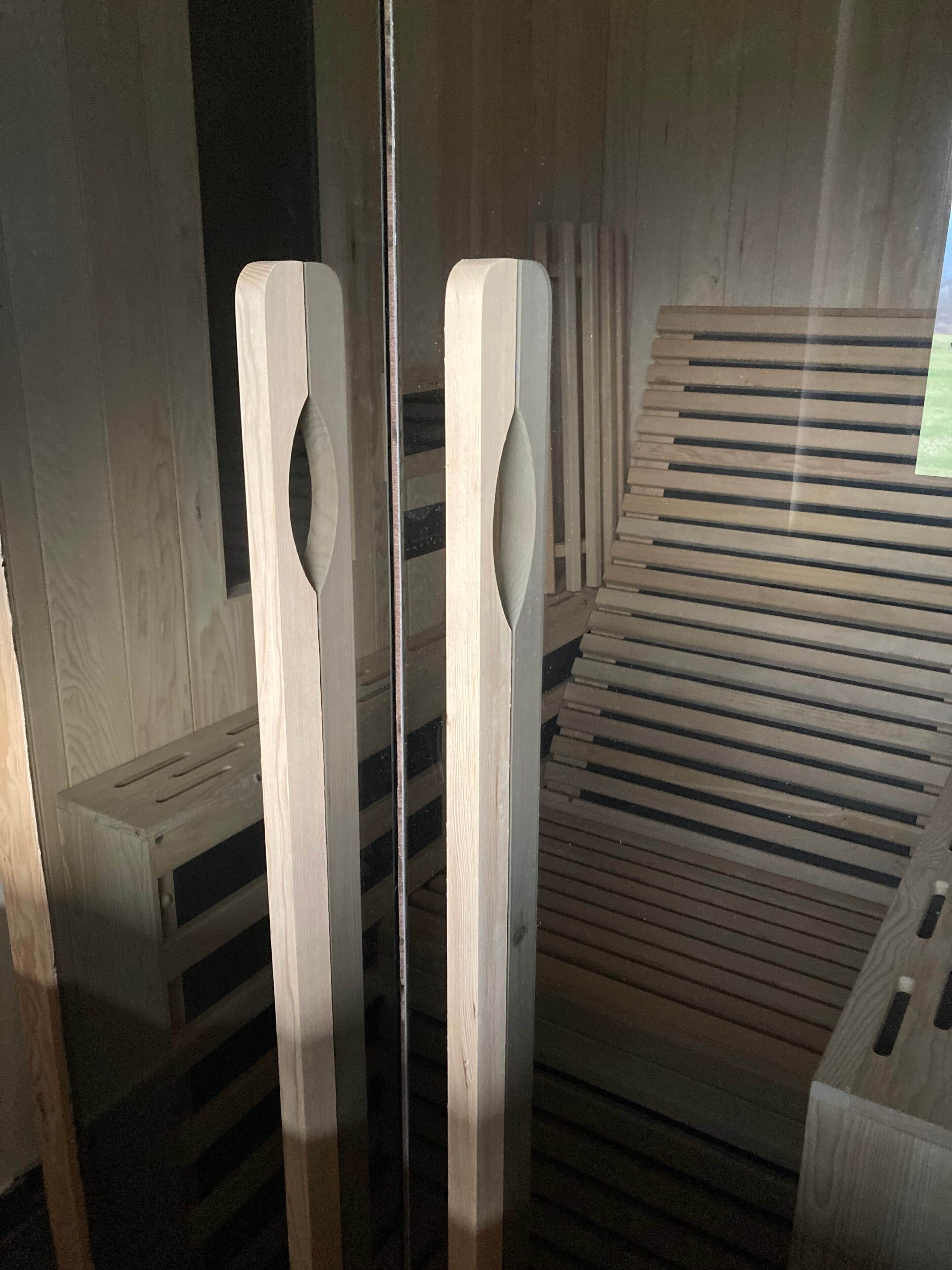 A wooden bench with slatted design, a wooden wall with vertical lines, and a reflective surface.