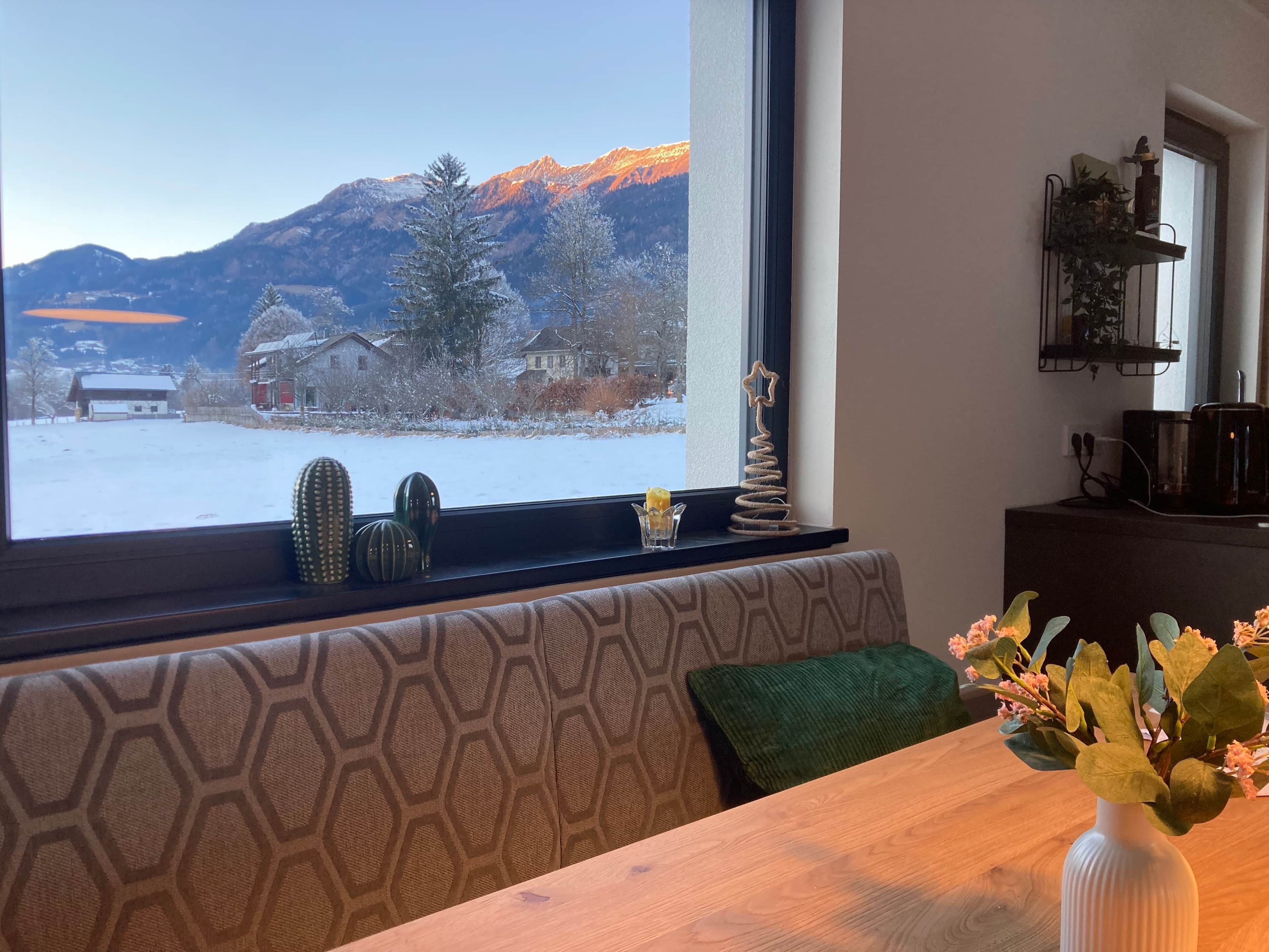 A room with a large window overlooking a snowy landscape and mountains.