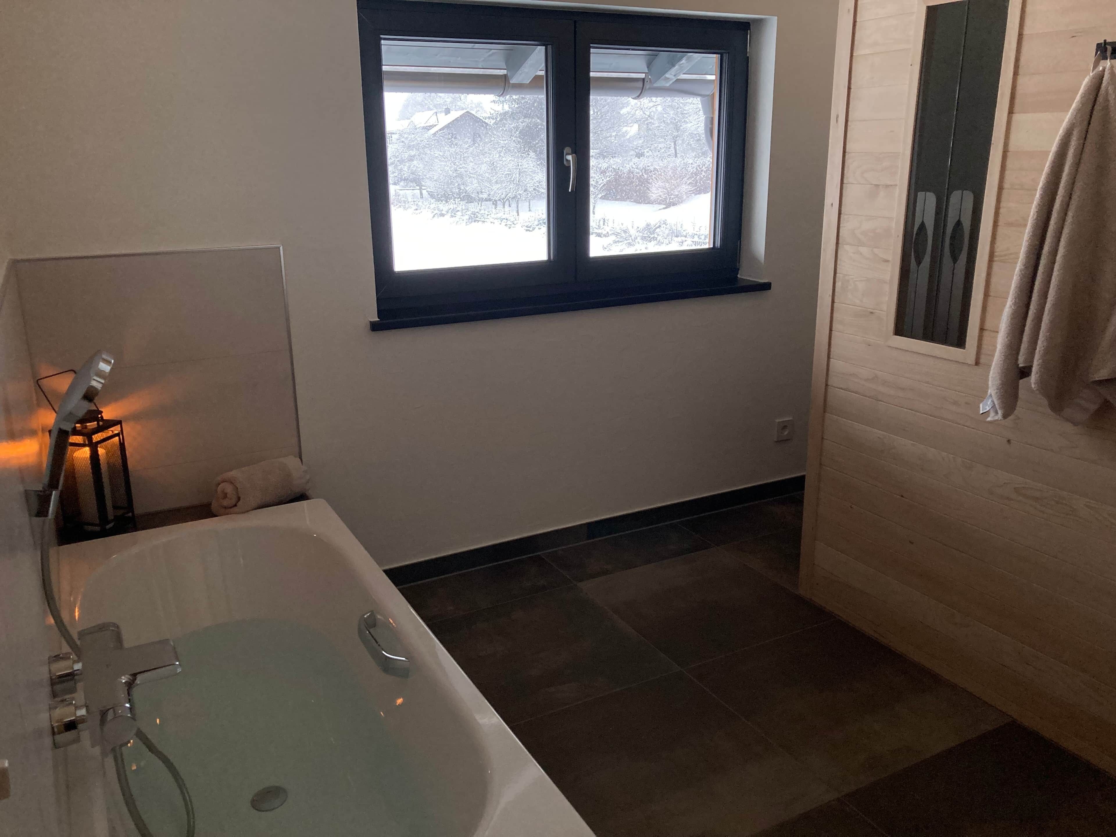 A bathroom with a bathtub, a window, and a towel rack.