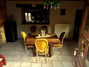 A dining area with a wooden table and chairs, a bar area with shelves, and a fire extinguisher. - Dog-friendly Home With Bubble Bath (Bouillon)