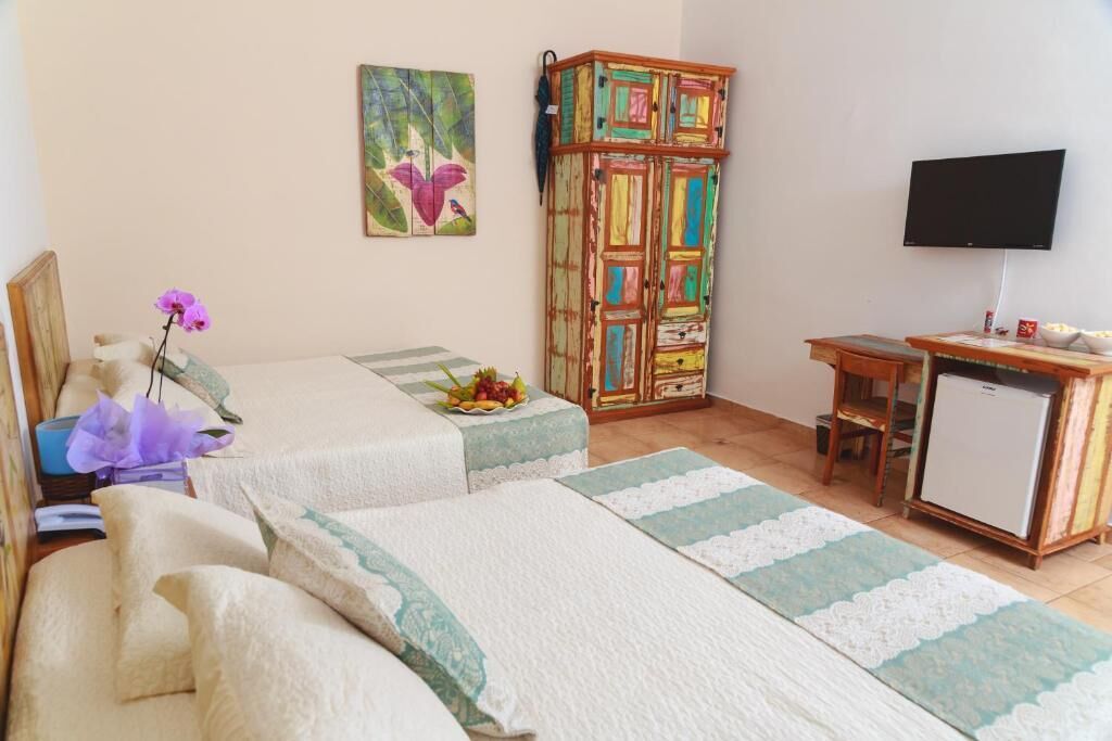 A hotel room with two beds, a TV, a small fridge, and a colorful cabinet.