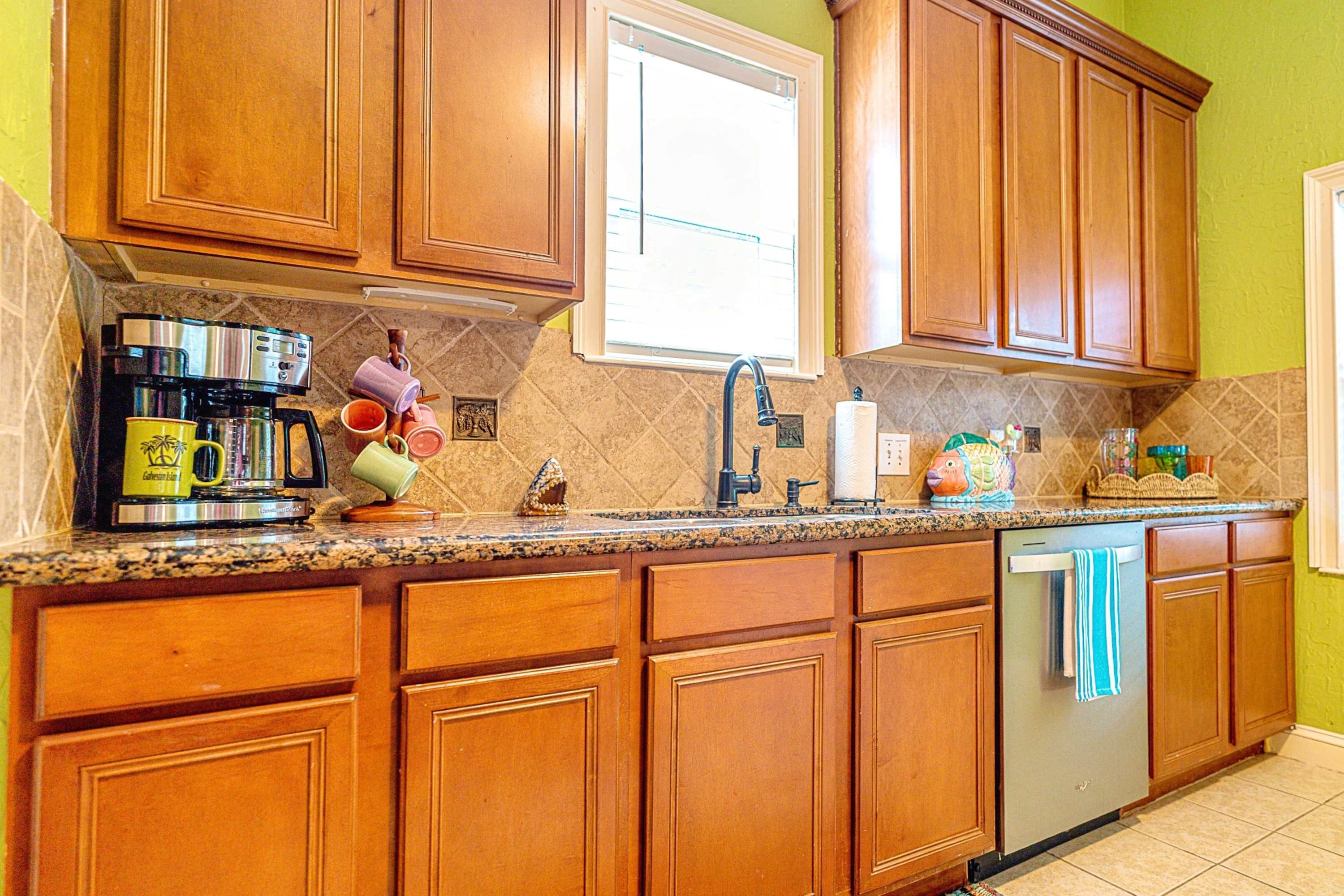 A kitchen with wooden cabinets, a stainless steel dishwasher, and a coffee maker.