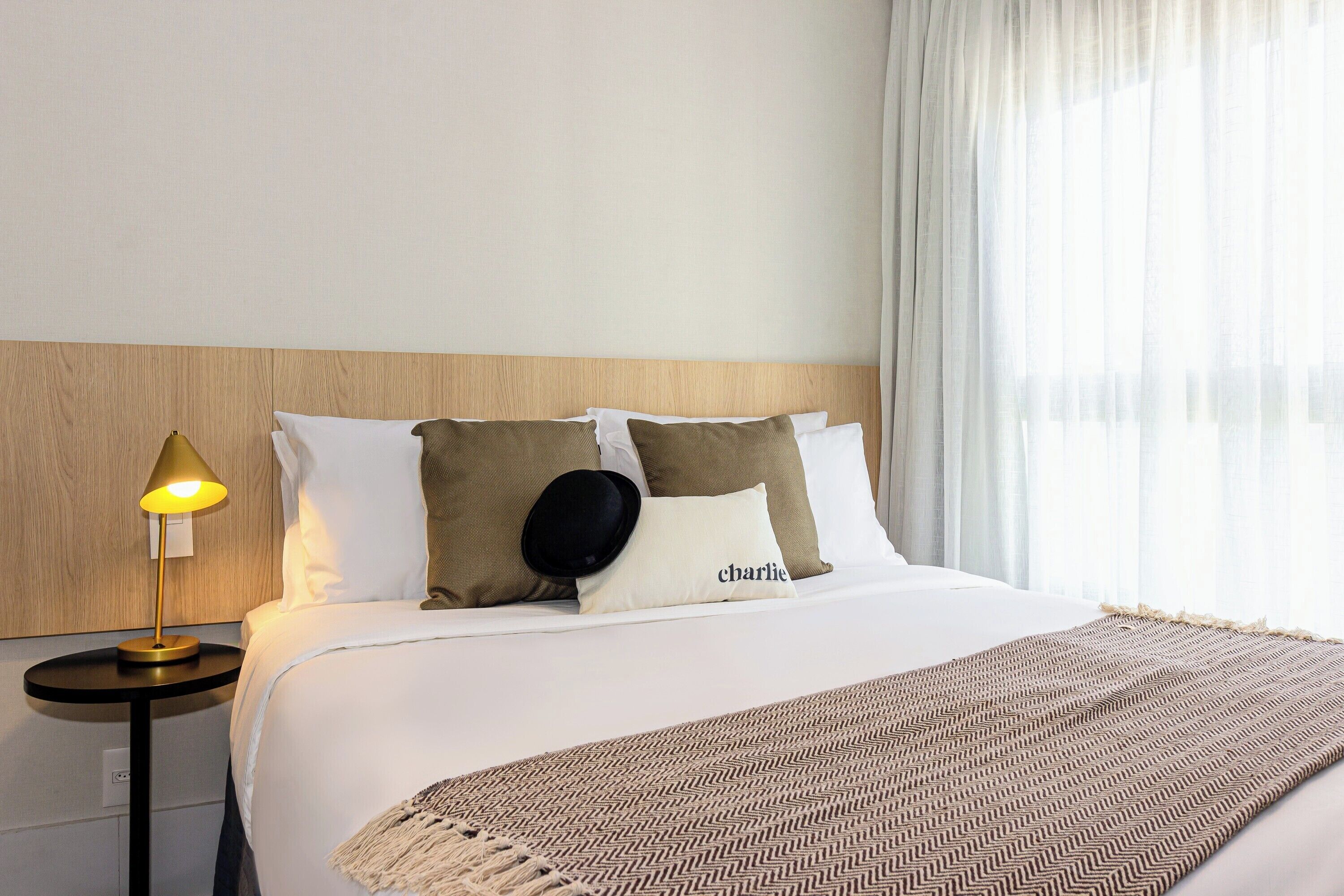 Ein Hotelzimmer mit Bett, Nachttischlampe und einem fenster mit Vorhängen.