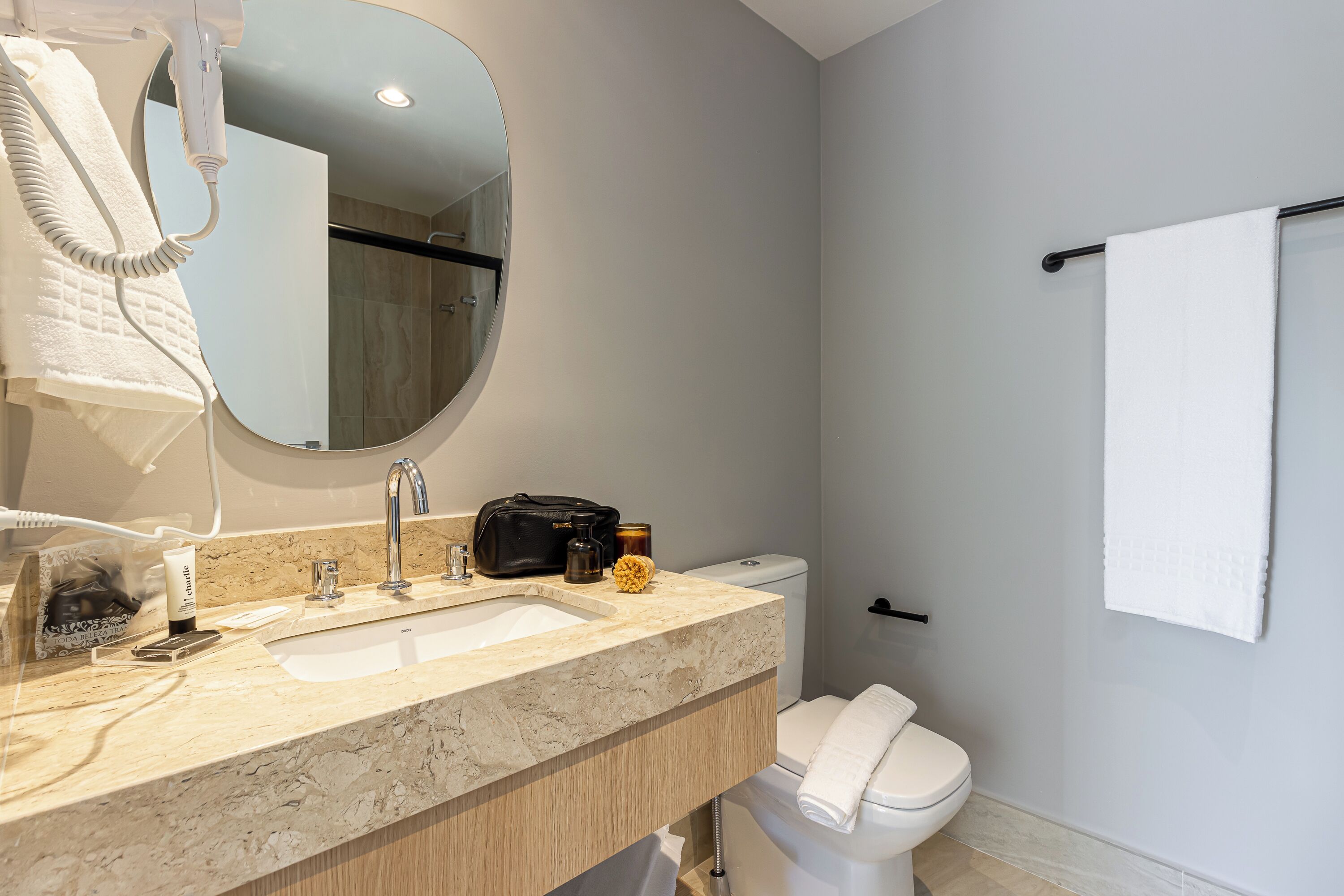 A bathroom with a sink, mirror, towel rack, and toilet.
