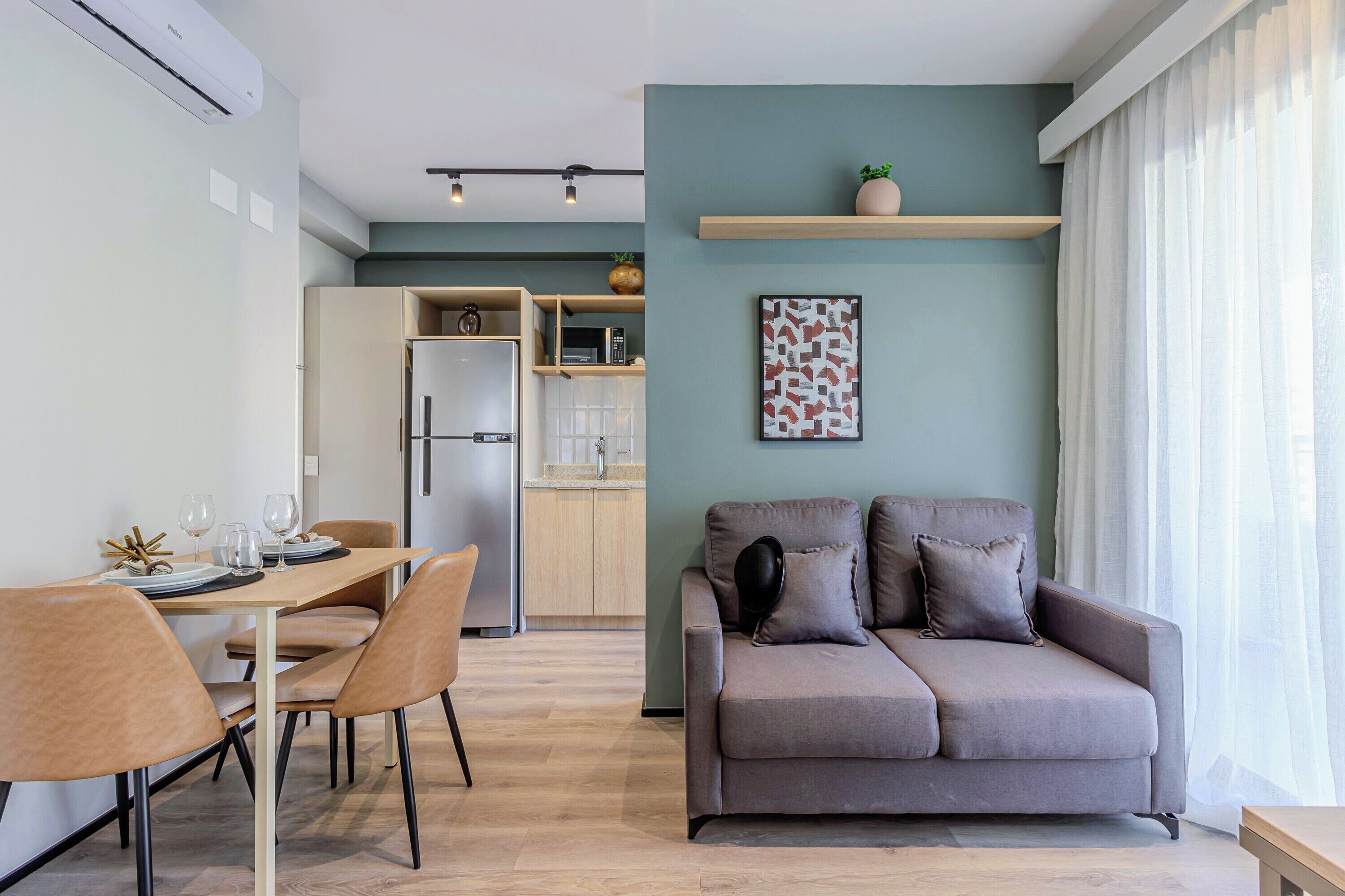 Een moderne woonruimte met een eethoek, bank, keuken en een wandplank.