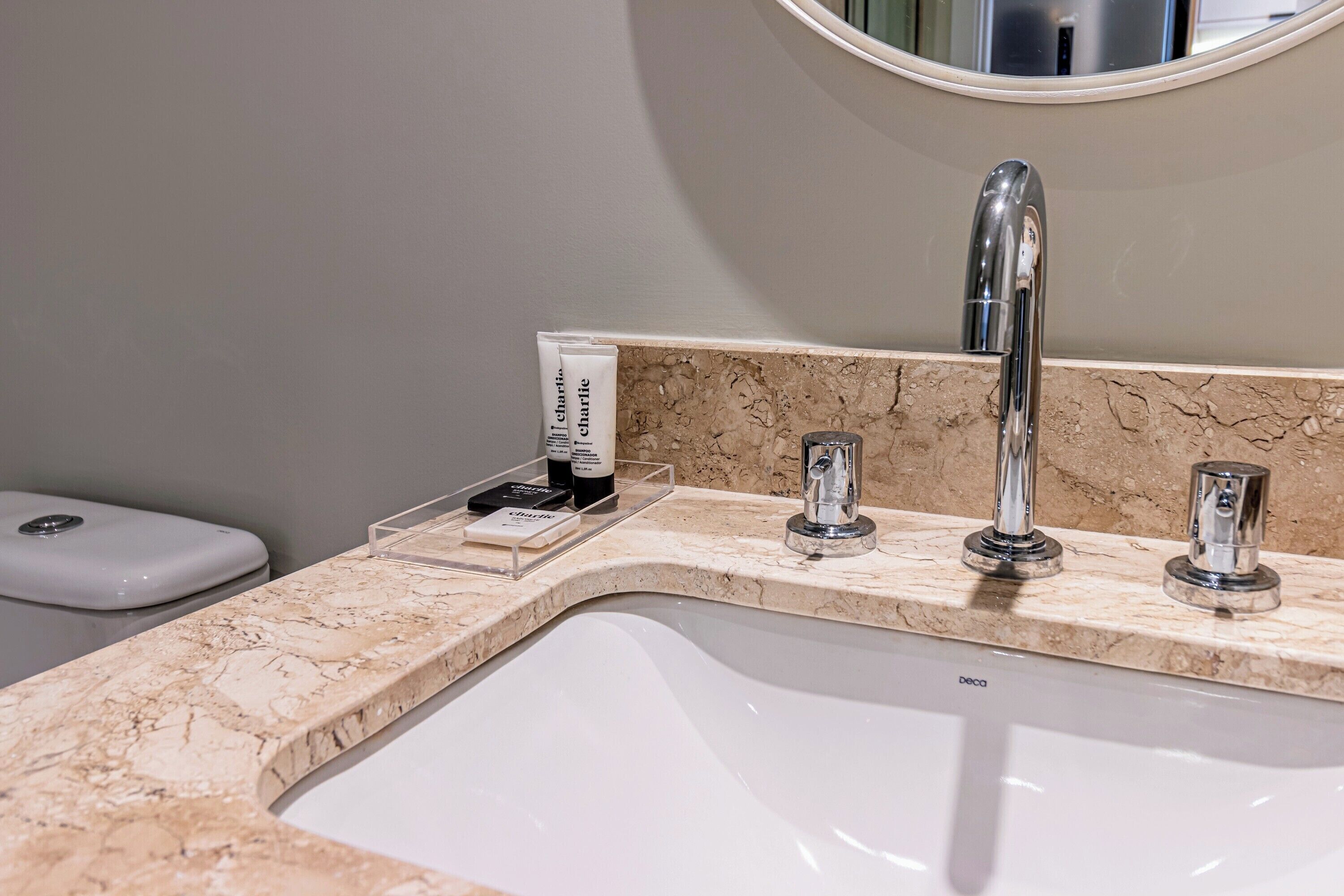 A bathroom with a marble sink, a mirror, and a white toilet.