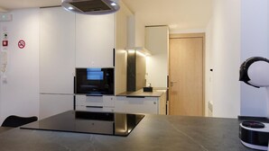 A modern kitchen with a built-in oven, microwave, and a sleek countertop. - Apartamentos Linda by Clabao (Pamplona)