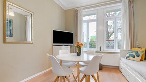 Un salon moderne comprenant un coin repas, un téléviseur à écran plat et un canapé agrémenté de coussins décoratifs.