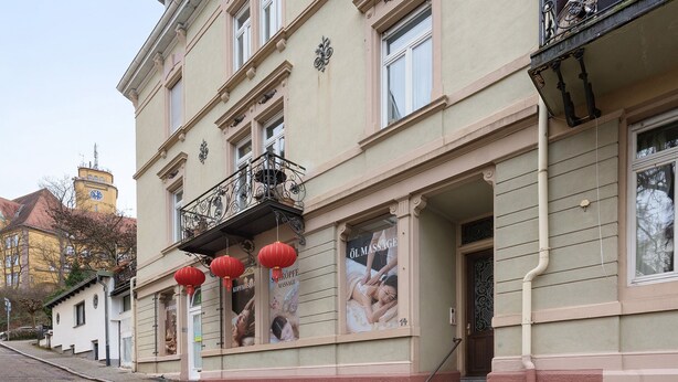 Un bâtiment doté d’un balcon, d’une porte et d’une fenêtre ornée d’une affiche.