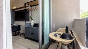 Una habitación moderna con comedor, una pequeña mesa con un sombrero y una botella, y una puerta de cristal que da a otra habitación.