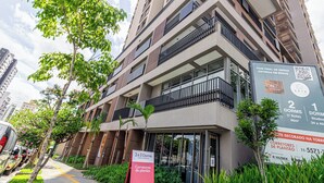 Un edificio residencial de varios pisos con balcones, un letrero que indica 2 dormitorios y un código QR para más información.