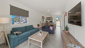 A modern living room with a teal sofa, a wooden coffee table, and a TV mounted on the wall. - Ocean Hibiscus Punta Azul Resort  (Sabana Westpunt)