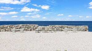A pebble beach with stone benches and a stone wall, overlooking the sea. - Ocean Hibiscus Punta Azul Resort  (Sabana Westpunt)