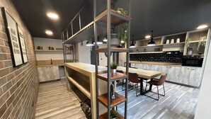 Een moderne keuken met een houten aanrecht, een ingebouwde bank en een centraal eiland met zitplaatsen. Er staan planten op de planken en er hangt een lamp.