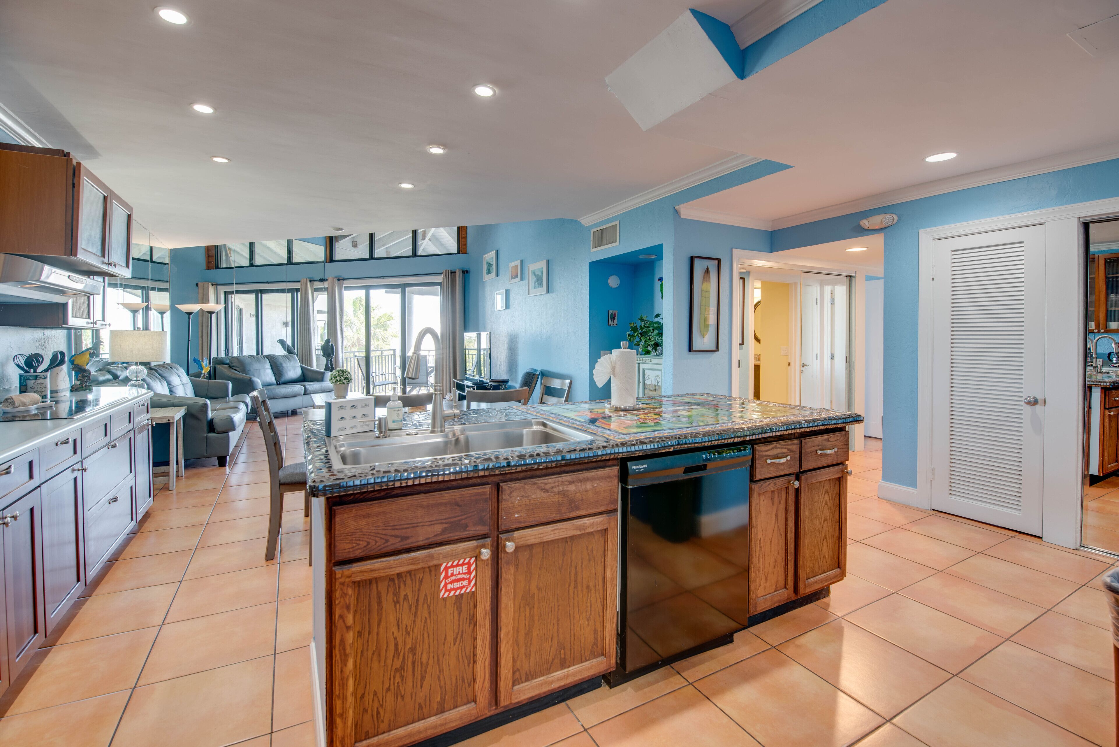 A spacious kitchen with wooden cabinets, a large island with a sink, and a dining area with a sofa.