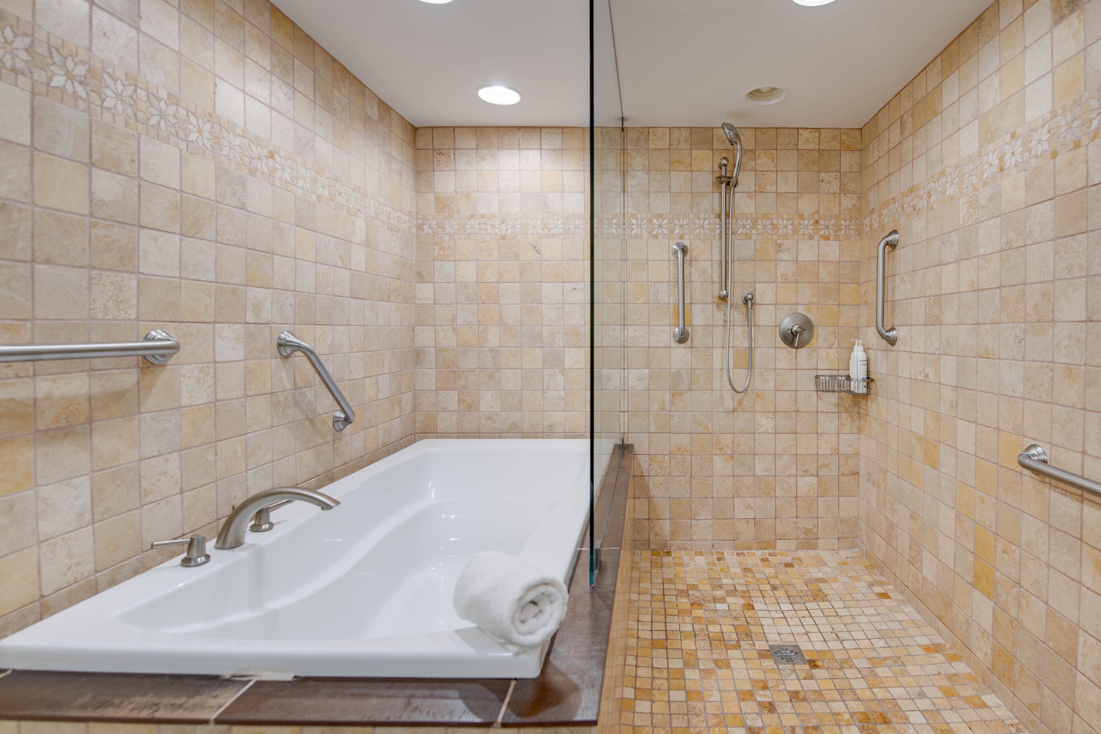 Un bagno moderno con vasca, doccia e maniglioni.