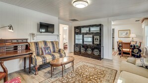 Una sala de estar con un escritorio de madera, un sofá, un televisor y un mueble decorativo.