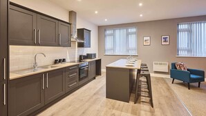A modern kitchen with dark cabinets, a central island, and a bar stool.