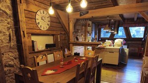 Un'area pranzo rustica in legno, con un tavolo, sedie e un orologio appeso al muro.