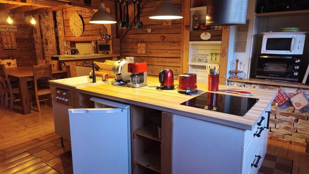 Una cucina compatta con pareti in legno, un'isola centrale con lavello, microonde e piano cottura.