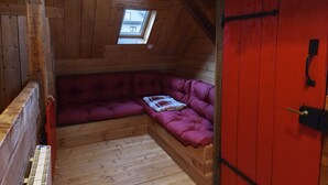 Accogliente camera mansardata con soffitto in legno, una porta rossa e un piccolo velux.