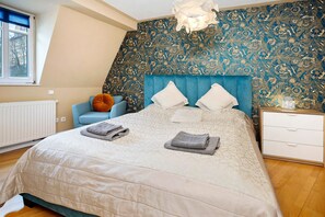 Ein Schlafzimmer mit einem Bett, einem Sessel, einem Nachttisch und einer Wand mit Muster.