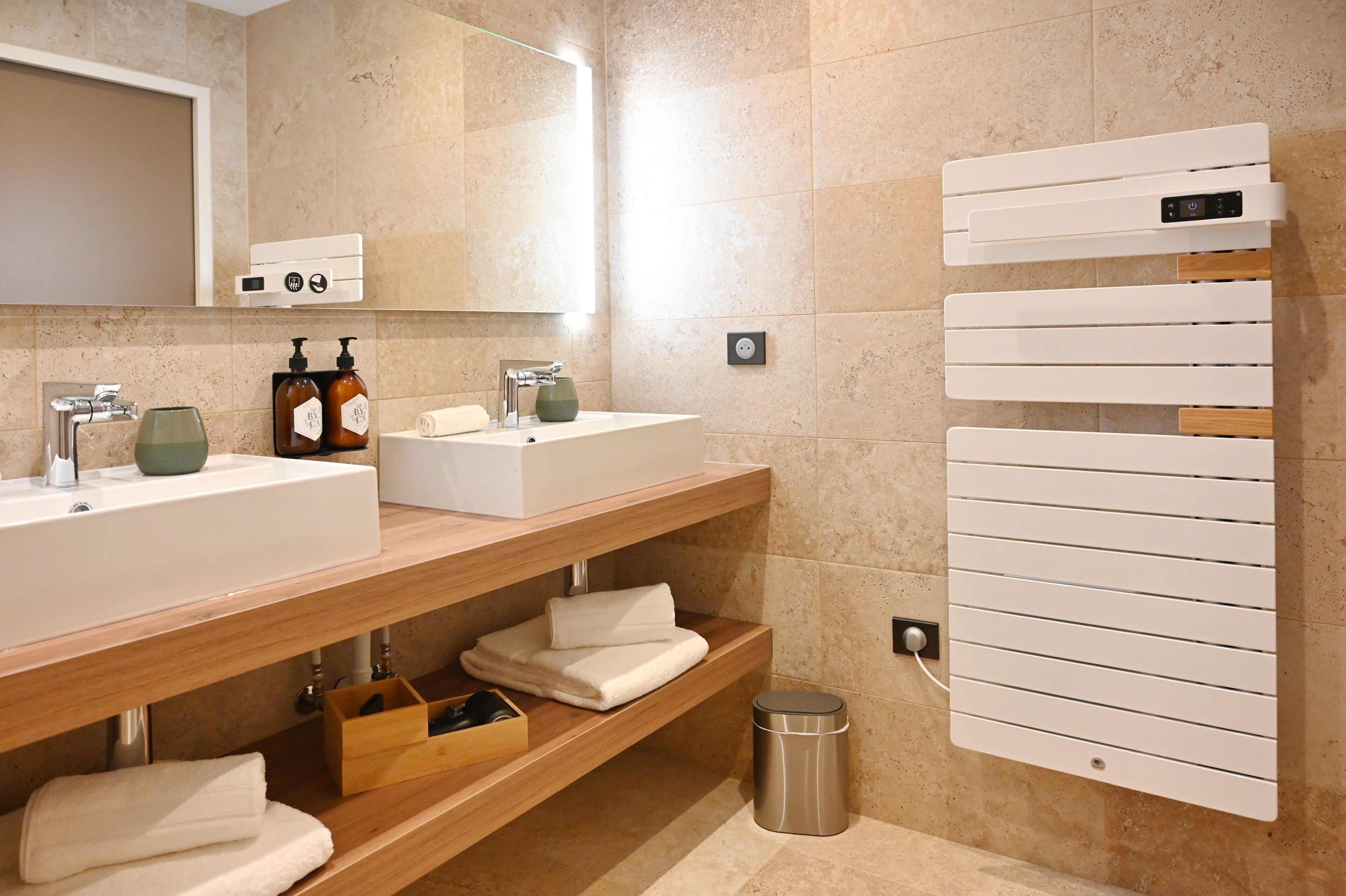A modern bathroom with two sinks, a mirror, and a towel rack.