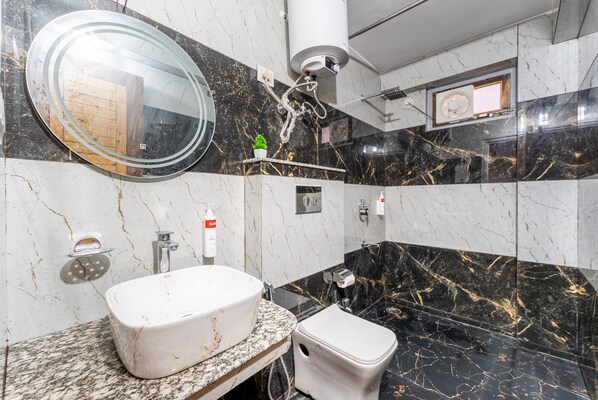 A bathroom with a white sink, a round mirror, a toilet, and a shower area.
