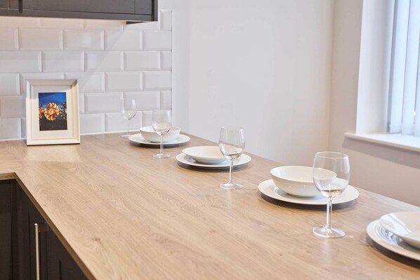 A kitchen counter with white plates and wine glasses arranged for dining.