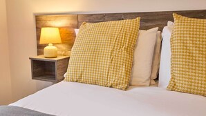 A neatly made bed with patterned pillows, a bedside lamp, and a wooden headboard.