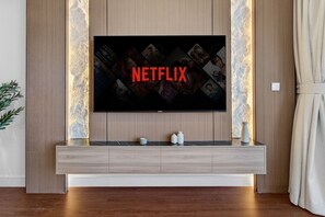 Un téléviseur à écran plat fixé au mur, avec un meuble en bois placé en dessous.