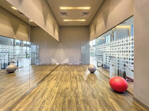Un hall d’entrée spacieux doté d’un plancher en bois, de murs recouverts de miroirs et de ballons d’exercice.